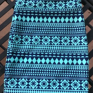 May include: A turquoise and navy blue skirt with a geometric pattern. The pattern features squares, triangles, and diamonds.
