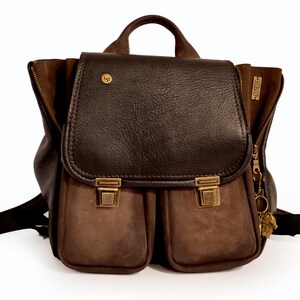 May include: A brown leather backpack with a flap closure and two front pockets. The backpack features a top handle, adjustable straps, and brass-colored hardware. The bag has a vintage aesthetic.