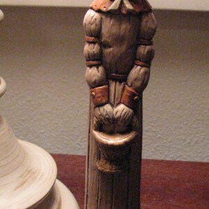 Pu&ograve; includere: Una statuetta in ceramica di un coniglio che indossa un cappello e un vestito. Il coniglio tiene un secchio nelle sue mani. La statuetta &egrave; dipinta in tonalit&agrave; di marrone e bianco.