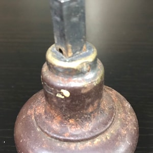 May include: Close-up of a vintage door knob with a brass base and a metal shaft. The knob is brown and has a worn, aged appearance.