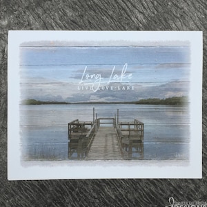 May include: A watercolor-style illustration of a wooden dock extending over a calm lake. The sky is a soft blue with a few clouds. The text "Long Lake" and "Live Love Lake" is written in white on a blue wooden background.