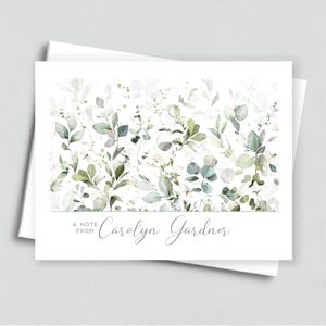 May include: A white card with a watercolor design of green and white leaves. The text "A Note From Carolyn Gardner" is printed at the bottom of the card.