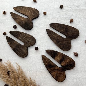 K&ouml;nnte beinhalten: Vier ausgeschnittene Holzformen von Hirschschenkeln in dunkelbrauner Farbe. Die Formen sind auf einem wei&szlig;en Hintergrund angeordnet.