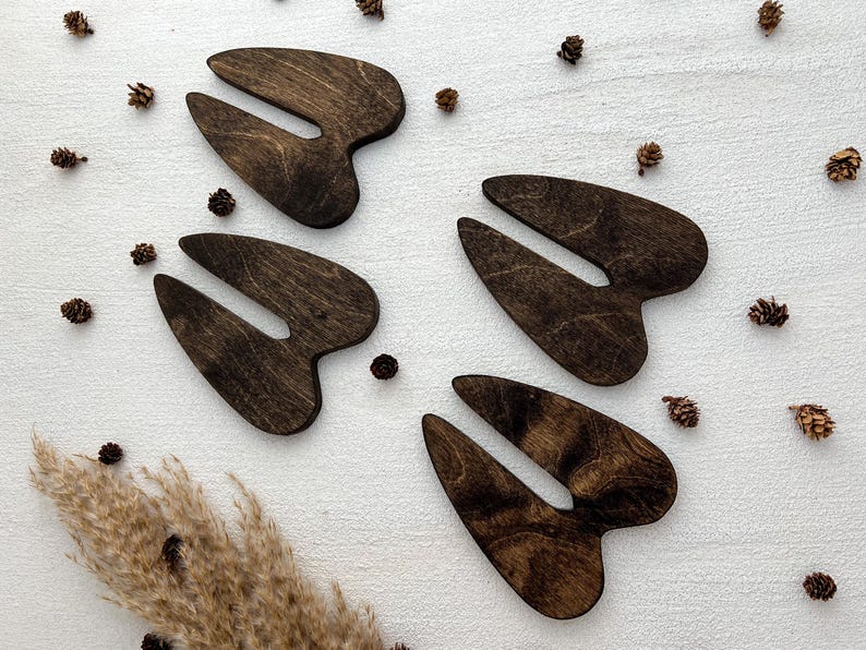 K&ouml;nnte beinhalten: Vier ausgeschnittene Holzformen von Hirschschenkeln in dunkelbrauner Farbe. Die Formen sind auf einem wei&szlig;en Hintergrund angeordnet.