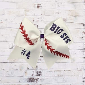 May include: White baseball-themed hair bow with red stitching and the text "BIG SIS #4" in purple glitter.