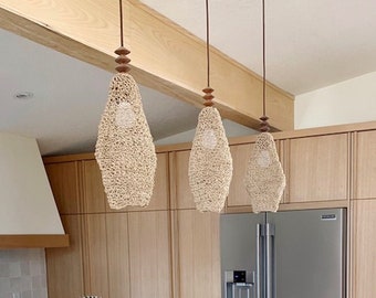 May include: A modern kitchen island with a white quartz countertop and brown leather bar stools. Three woven pendant lights hang above the island.