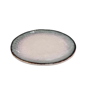 May include: A ceramic plate with a light cream center and a blue-green rim. The plate has a slightly irregular shape and a dark brown edge. The plate is suitable for serving food.
