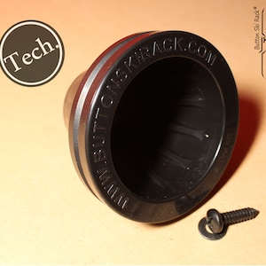 May include: Black plastic ski rack mount with a red and black stripe. The mount has the text "www.buttonskirack.com" printed on the side. A screw and washer are included.