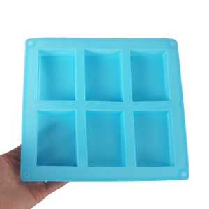May include: A light blue silicone mould with six rectangular cavities. The mould is designed for making soap, chocolate, or other small treats.