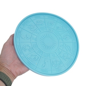 May include: A light blue silicone zodiac wheel with all 12 zodiac signs and their symbols. The wheel is circular and has a raised sun in the center.