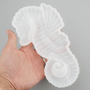 May include: White silicone mould shaped like a seahorse. The mould has a detailed design with ridges and a textured surface.