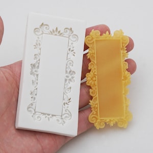 May include: A white silicone mold with a rectangular frame design. The mold is used to create a decorative frame for cakes or other desserts. A yellow frame made with the mold is shown next to it.