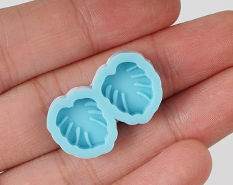 May include: Two silicone molds for making resin crafts. Each mold is shaped like a monstera leaf with a light blue interior.