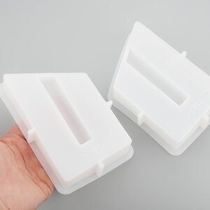 May include: Two white silicone molds for making resin crafts. The molds are shaped like a rectangle with a vertical slot in the center. The molds are made of flexible silicone and are easy to use.