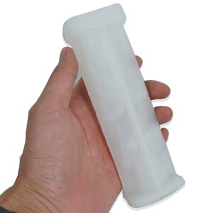 May include: White silicone mold for making a cylindrical object. The mold is smooth and has a slightly textured surface.