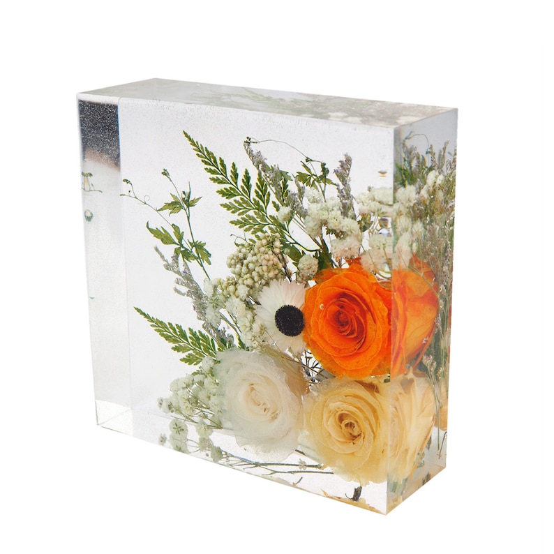 Pode incluir: Um cubo transparente cheio de um arranjo de flores preservadas. O arranjo inclui rosas laranja e creme, an&eacute;monas brancas e respira&ccedil;&atilde;o de beb&ecirc; branca.