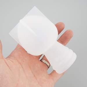 May include: White silicone mold for making resin crafts. The mold is shaped like a bottle with a round top.