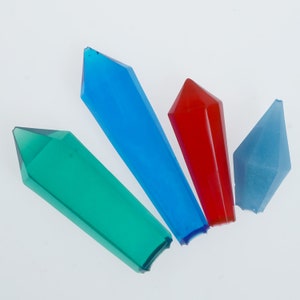 May include: Four crystal shapes in different colors: blue, green, red, and light blue. The crystals are all pointed and have a translucent appearance.