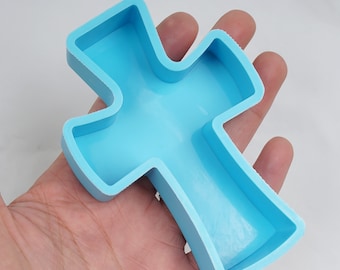 May include: A light blue silicone mould shaped like a cross. The mould is designed for making crafts or decorations.