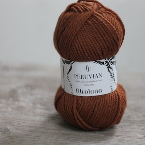 May include: A ball of brown Peruvian highland wool yarn from Filcolana. The label reads "PERUVIAN 100% peruvian highland wool 100m/50g". The yarn is a rich, warm brown color, perfect for knitting and crochet projects.