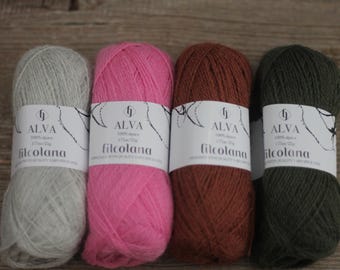 Puede incluir: Cuatro ovillos de hilo Alva en diferentes colores: gris, rosa, marrón y verde. El hilo es 100% alpaca y está hecho por Filcolana.