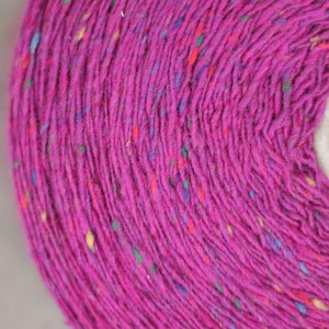 Puede incluir: Primer plano de un carrete de hilo rosa con motas multicolores. El hilo est&aacute; enrollado firmemente alrededor de un n&uacute;cleo de cart&oacute;n.