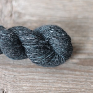 May include: A skein of dark blue yarn with flecks of white and teal.