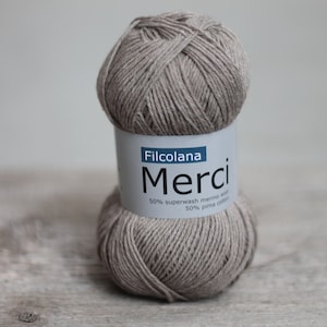May include: A ball of beige yarn labeled "Filcolana Merci 50% superwash merino wool 50% pima cotton"