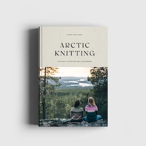 Puede incluir: Portada de libro con una foto de dos personas sentadas en una roca con vistas a un lago y un bosque. El título del libro es "Arctic Knitting: The Magic of Nature and Colourwork".