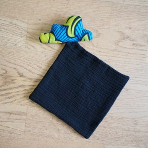 Può includere: Una pochette in tessuto nero con un cuore in tessuto a fantasia colorata sopra. La pochette è realizzata in un materiale morbido e testurizzato.