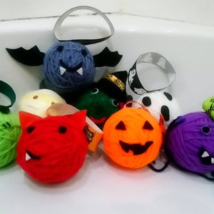Puede incluir: Una colección de ocho bolas de lana decoradas con temas de Halloween. Las bolas de lana son de varios colores, incluyendo verde, rojo, naranja, morado, azul y blanco. Cada bola de lana tiene un personaje diferente de Halloween, como un fantasma, una calabaza, un vampiro y una bruja.