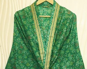 May include: A green floral patterned kimono robe with a gold trim. The robe is hanging on a wooden hanger. The robe is tied at the waist with a matching fabric tie. The fabric has a floral pattern in shades of green and brown.