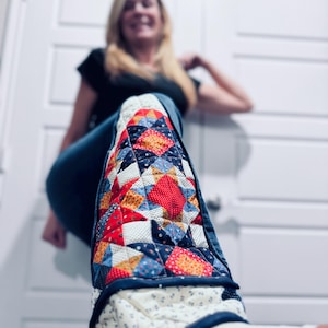 May include: A pair of blue denim jeans with a patchwork quilt design on the bottom of the legs. The quilt is made of red, blue, white, and yellow fabric.