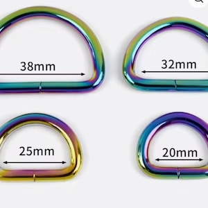 May include: Four iridescent rainbow-colored D-rings arranged in a grid. The metal rings feature labeled internal widths of 38mm, 32mm, 25mm, and 20mm. Each D-ring has a smooth, curved top and a flat base, showcasing a metallic gradient finish.