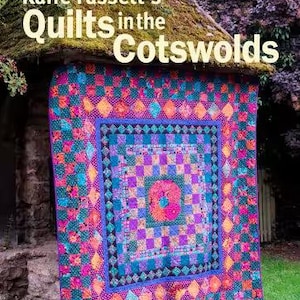 May include: A book titled Kaffe Fassett's Quilts in the Cotswolds: 20 designs for patchwork and quilting. The cover features a vibrant, multi-colored quilt with a geometric pattern in shades of pink, purple, orange, teal, and blue.