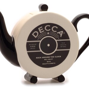 May include: Black and white ceramic teapot shaped like a vintage record. The teapot features a black and white image of a record label with the text "DECCA", "RECORD NO 9-29124 186163)", "Vocal chorus by Bill Haley", "ROCK AROUND THE CLOCK BILL HALEY WITH HALEY'S COMETS".