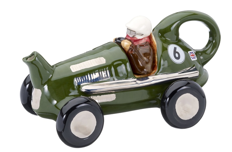 May include: Green ceramic teapot shaped like a vintage race car with a driver figurine. The car has a number "6" and a Union Jack flag on the side.