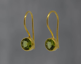 May include: A pair of gold earrings with green gemstone accents. The earrings have a simple, elegant design.
