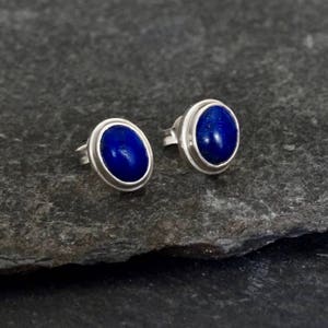 Pode incluir: Um par de brincos de prata com pedras de lapis-laz&uacute;li ovais.