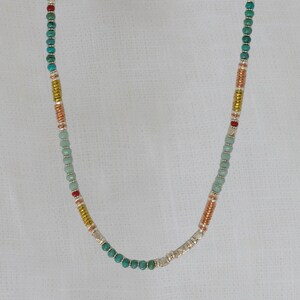 May include: A turquoise, silver, copper, and red beaded necklace. The necklace is made of small round beads and is approximately 18 inches long.