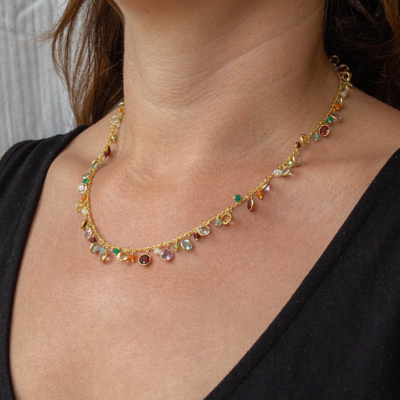 May include: A gold chain necklace with a variety of colorful gemstones, including green, blue, orange, and purple.