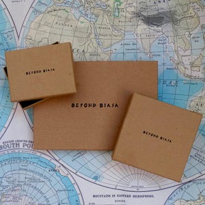 Pode incluir: Tr&ecirc;s caixas de cart&atilde;o castanho com o texto "Beyond Biasa" impresso nelas. As caixas est&atilde;o sobre um mapa do mundo.