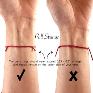 May include: A red string bracelet shown on a wrist with text instructions: Pull Strings. The pull strings should never exceed 0.25 - 0.5" in length and should remain on the under side of your wrist. A checkmark indicates the correct length.