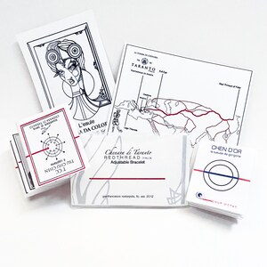 May include: A collection of white rectangular cards and paper inserts featuring black and red graphic illustrations, maps, and text including Chenara di Taranto, Redthread Italia, and Coup d'Etat. The designs depict stylized figures and diagrams.