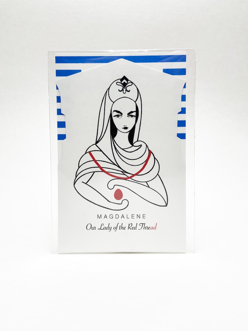May include: A rectangular card featuring a black and white line drawing of a figure wearing a head covering and a red thread draped around the shoulders, holding a red egg. The text reads MAGDALENE Our Lady of the Red Thread. Blue stripes appear.