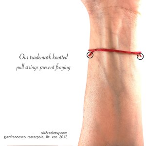 May include: A thin red string bracelet featuring knotted pull strings at both ends to prevent fraying. The text on the image reads: Our trademark knotted pull strings prevent fraying, six8red.etsy.com, gianfrancesco rastarpola, llc. est. 2012.