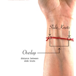 May include: A thin red string bracelet featuring two adjustable slide knots. The image includes text labels pointing to the slide knots and the overlap section, with the text 'Slide Knots', 'Overlap', and 'distance between slide knots' visible.