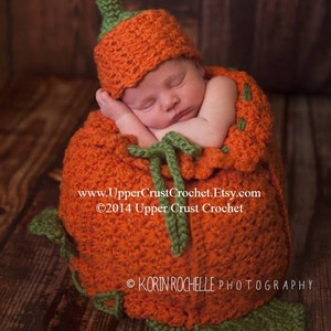 May include: A newborn baby is sleeping inside a crocheted pumpkin costume. The costume is orange with green leaves and a stem. The baby is wearing a matching crocheted pumpkin hat. The image includes the text "www.UpperCrustCrochet.Etsy.com ©2014 Upper Crust Crochet" and "KORIN ROCHELLE PHOTOGRAPHY".