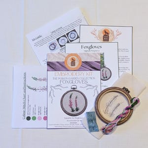May include: Embroidery kit for beginners featuring a design of purple foxgloves. The kit includes a hoop, fabric, floss, and instructions. The kit is labelled "The Poison Garden Collection: Foxgloves".