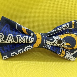 May include: A blue and yellow bow tie with the word "RAMS" and a football helmet graphic.